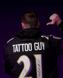 a man wearing a black jersey that says tattoo guy on the back