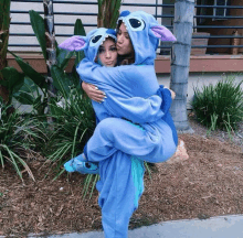 a woman in a stitch costume is carrying another woman on her shoulders