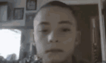 a young boy with a shaved head is looking at the camera in a room .