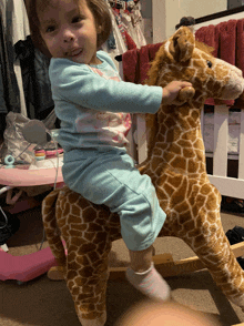 a little girl is riding a stuffed giraffe