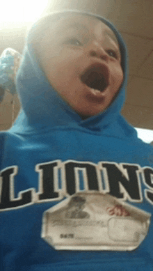 a boy wearing a blue lion 's hoodie with his mouth wide open