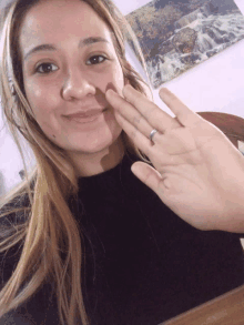 a woman wearing a ring on her finger is smiling