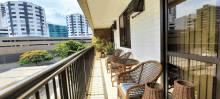 a balcony with wicker chairs and tables with a view of a city