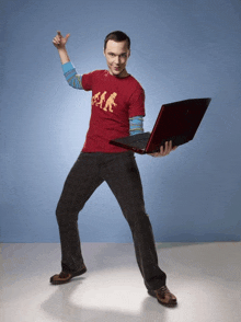 a man wearing a red shirt that says ' ear ' on it is holding a laptop