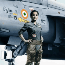 a woman in a military uniform stands in front of a plane with the name tejas on it