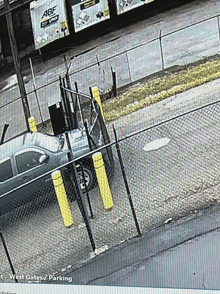 a car is parked in front of a fence that says west gates parking on it