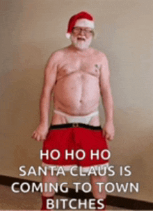 a shirtless man dressed as santa claus is standing in front of a sign that says ho ho ho santa claus is coming to town bitches