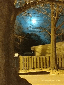 a full moon shines brightly over a wooden fence