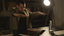 a man sitting at a desk looking at a book with a bottle of hand sanitizer in front of him