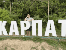 a man stands in front of large white letters that spell out kapit