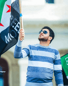 a man in a blue and white striped sweater is holding a flag that says moer