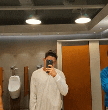 a man is taking a picture of himself in a public restroom