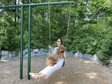 a woman is sitting on a swing with two dogs