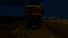 a scania truck is parked on the side of a road at night