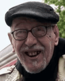 a close up of a man wearing glasses and a hat smiling .