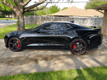 a black sports car with red brake calipers is parked on a driveway