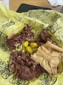 a corned beef sandwich with pickles and mustard on a yellow paper that says ' corned beef ' on it