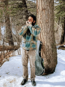 a man in a plaid jacket playing a harmonica in the snow