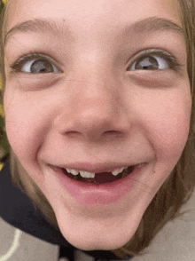 a young girl with a missing tooth smiles with her eyes closed