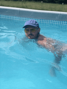 a man in a blue hat and sunglasses is swimming in a swimming pool