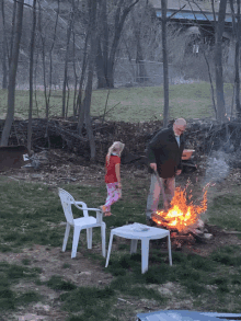 a man and a little girl are standing around a campfire