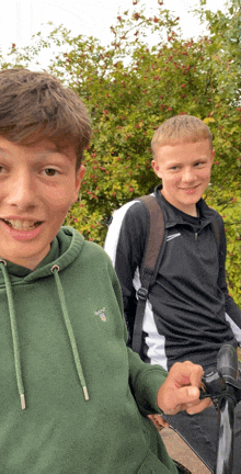 a boy wearing a green gant hoodie is standing next to another boy