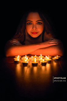 a photo of a woman surrounded by lit candles with the hashtag photolab at the bottom