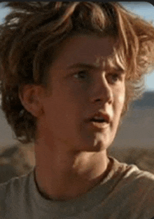 a close up of a young man 's face with long hair .