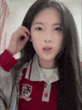 a girl wearing a red shirt with a shield on it that says ' jd ' on it