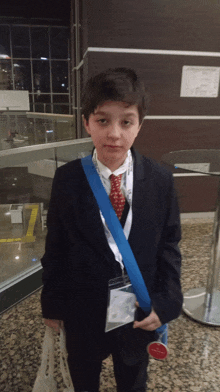 a young boy wearing a suit and tie with a lanyard around his neck that says ' istanbul ' on it