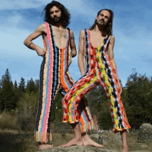 two men wearing colorful jumpsuits are standing next to each other in a field