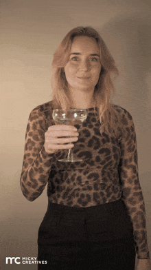 a woman in a leopard print top is holding a glass