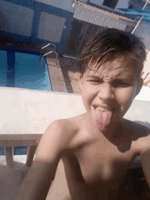 a young boy is sticking his tongue out in front of a pool .