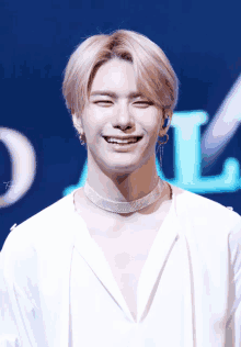 a young man wearing a choker and earrings smiles for the camera