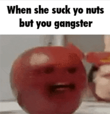 a red apple with a face on it and the words `` when she suck yo nuts but you gangster '' written on it .