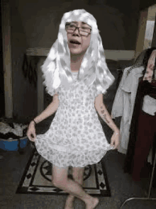 a person wearing a white dress and a white wig is standing in a room .