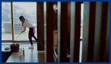 a woman is mopping the floor in a living room with a picture of a man in a suit on the wall behind her