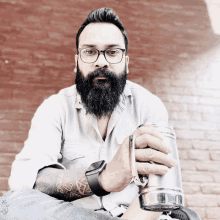 a man with glasses and a beard is holding a glass