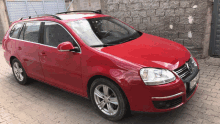 a red volkswagen is parked on a brick pavement