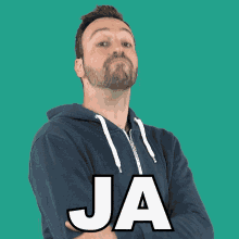 a man with a beard wears a blue hoodie with the word ja on the front