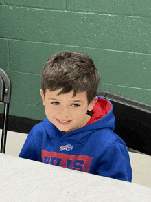 a young boy wearing a blue buffalo bills sweatshirt