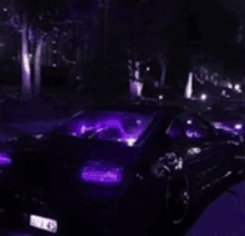 a purple car is parked in the dark with purple lights on .