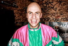 a man wearing a pink and green jacket with the word adidas on it