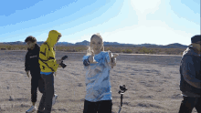 a group of people are standing in a dirt field and one of them is wearing a yellow hoodie that says boys