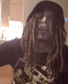 a man with dreadlocks is wearing a hat and a t-shirt