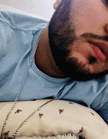 a man with a beard wearing a blue shirt and a chain around his neck