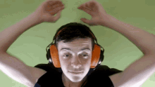 a young man wearing orange headphones is making a face