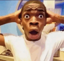 a man is making a surprised face while holding his head .