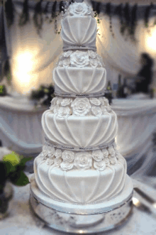 a white wedding cake with white roses and pearls