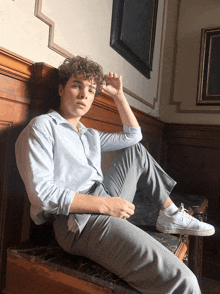 a young man with curly hair is sitting on a marble bench